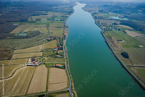 This captivating view showcases the Adour river winding through Urt, Landes. Surrounding farmland and peaceful homes highlight the natural beauty of the area, inviting exploration.