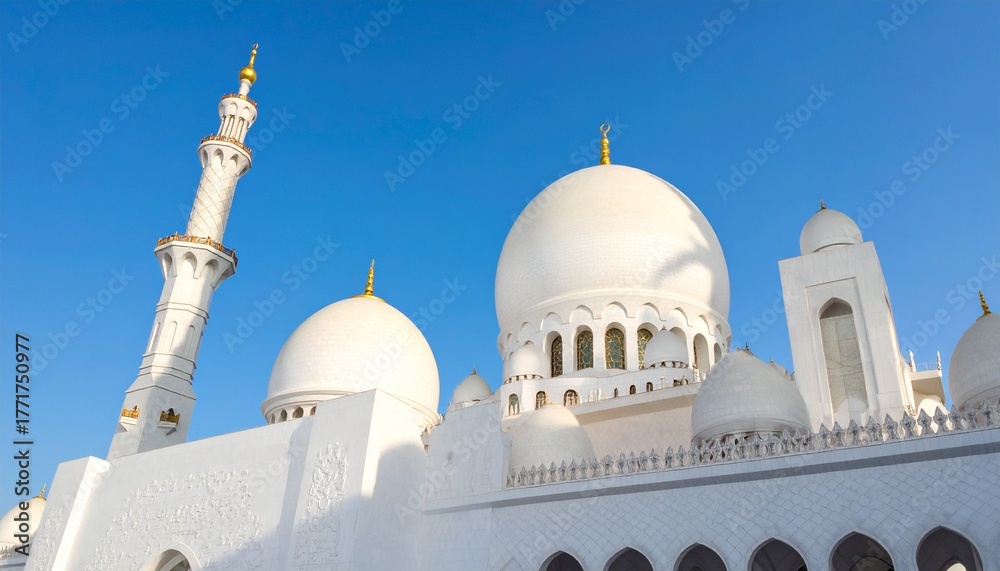 Obraz premium Beautiful white mosque with domes and tall minaret under blue sky, elegant Islamic architecture and cultural heritage exterior view.