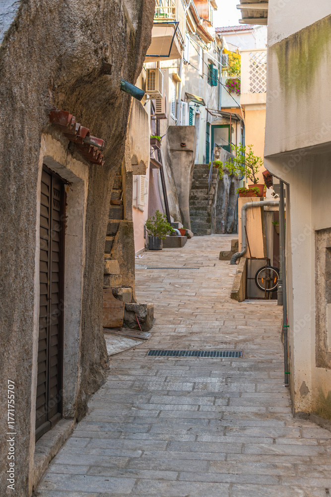 Fototapeta premium Charming stone alleyway in quaint european village with rustic architecture. Baska, Krk island, Croatia