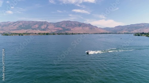 Aerial view of boat pulling tubes on mountain lake