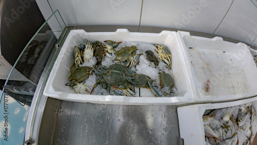 Fresh chilled crabs displayed on crushed ice at a seafood market.