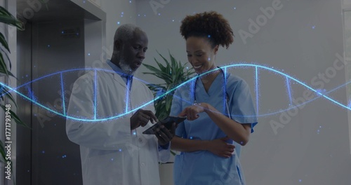 Doctor in labcoat and nurse in scrubs viewing tablet in clinic hallway, with DNA helix, stethoscope