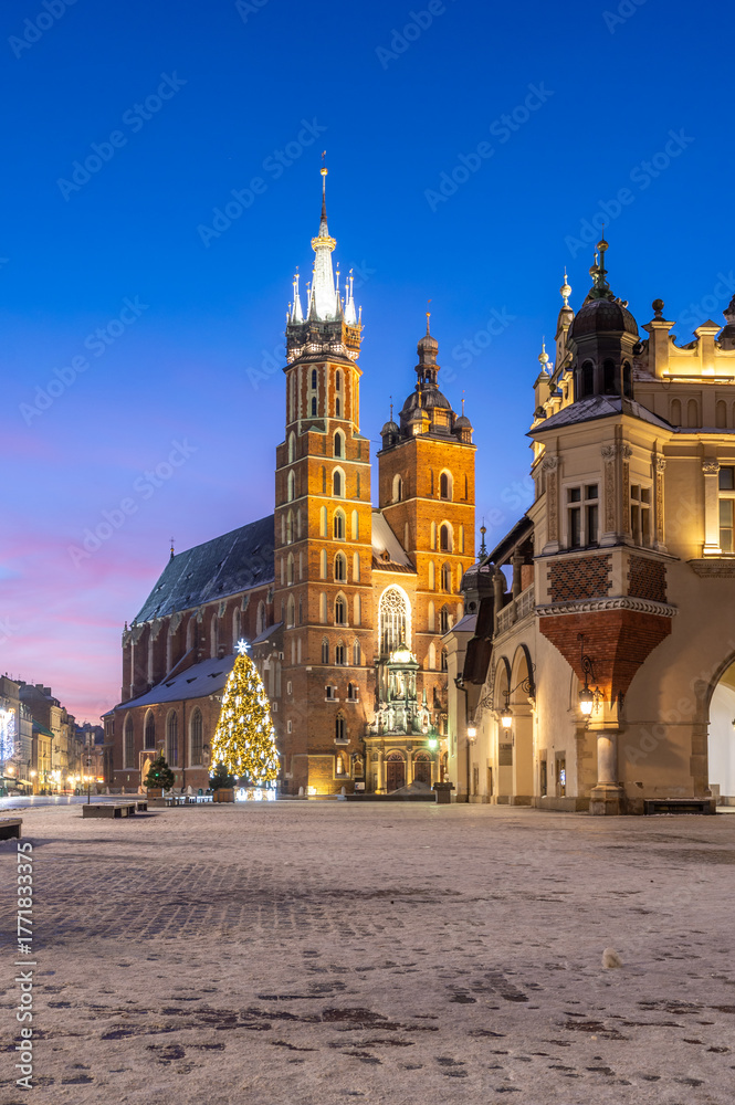 Naklejka premium St Mary's church and Cloth Hall fragment on snow covered Main Square in winter Krakow, illuminated in the dawn