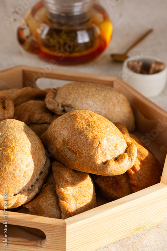 Homemade baked pies (pirozhki) with cabbage on a tray with tea. Traditional Russian, Ukrainian and Belarussian cuisine. Vertical orientation.