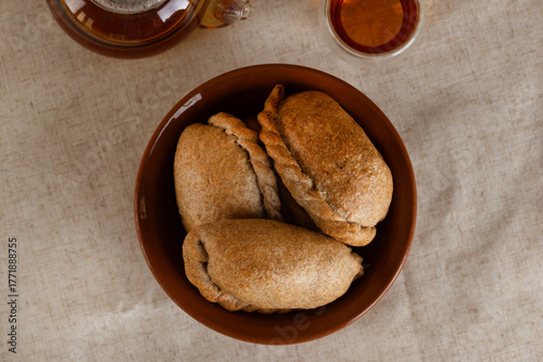 Traditional homemade pies with cabbage in the plate with tea on a table. Top view.