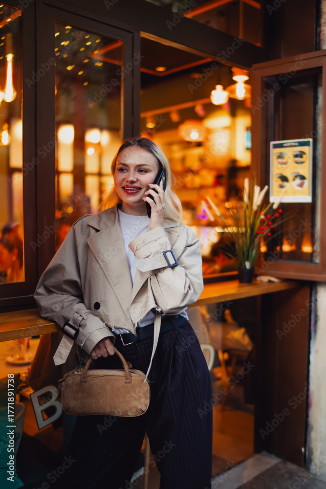 Fototapeta premium Woman standing outside, smiling while looking at smartphone