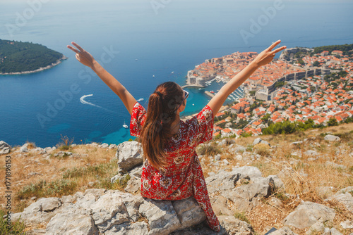 A cheerful tourist enjoying the breathtaking view of Dubrovnik from the picturesque hillside
