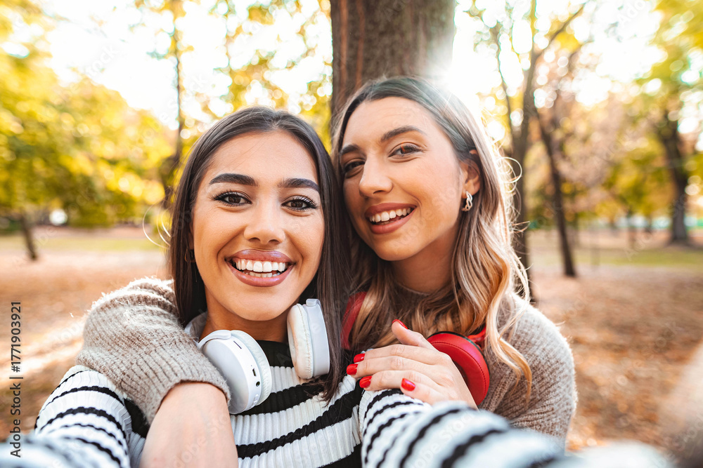 Obraz premium Joyful autumn moments shared by two friends in a sunlit park