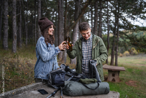 Tableau sur toile Happy couple camping, toasting beer bottles in forest