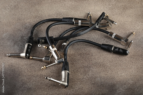 Guitar patches for connecting various pedal sound effects for electric guitars on a brown cement background.