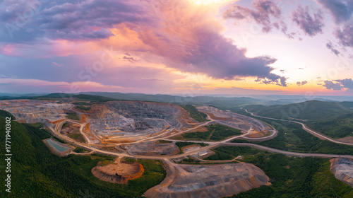 Foto Aerial view of expansive open pit mine at sunset with dramatic sky and lush surr