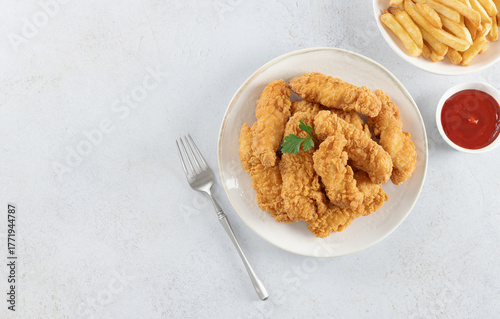 Crispy chicken strips with ketchup and French fries on a white background. Fast food. Copy space