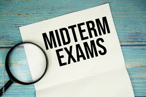 Photos Midterm Exams text written on notepad with magnifying glass flat lay on wooden b