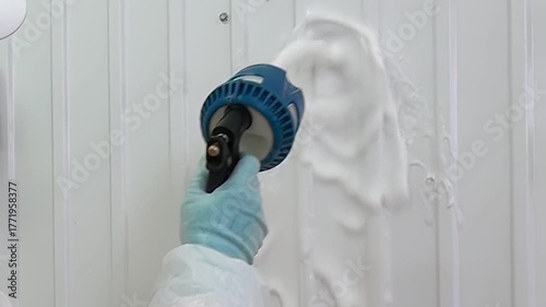 Foam is sprayed onto industrial walls, which are then cleaned by a person wearing protective gear. This process removes dirt, grime, and other impurities, ensuring a safe and hygienic workspace.