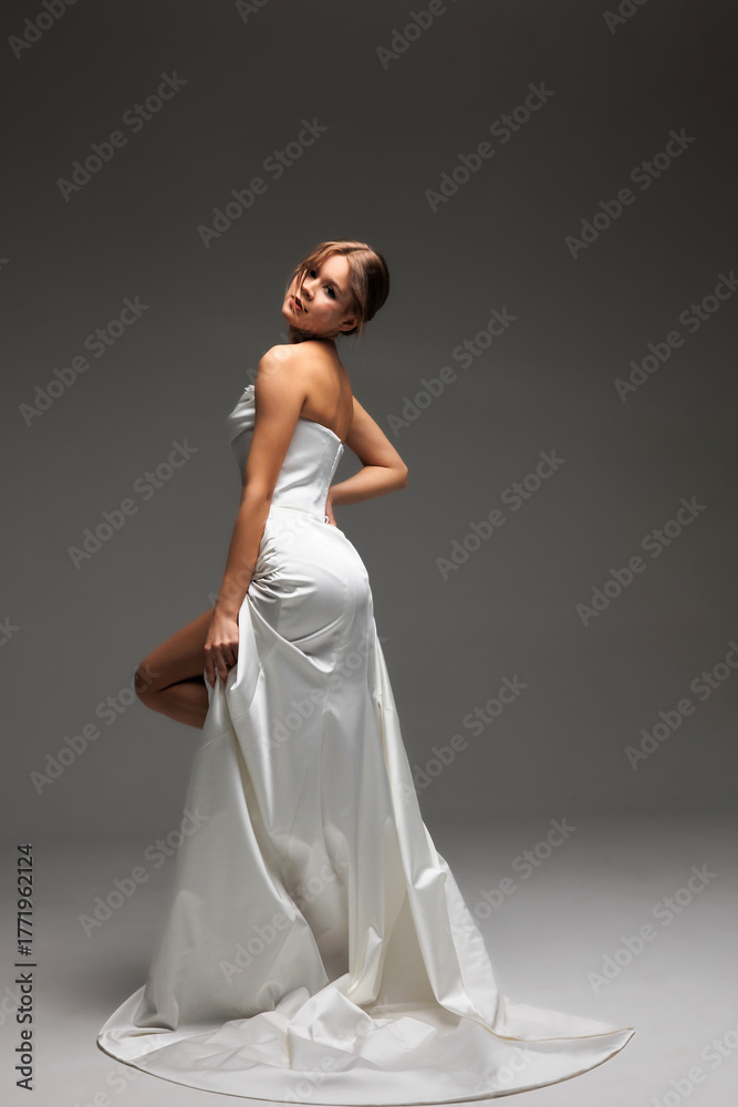 Naklejka premium Elegant bride showcasing modern bridal style in minimalist wedding gown with luxurious satin finish