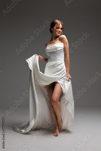 Elegant bride in modern white satin wedding dress showcasing minimalist style in soft natural light studio