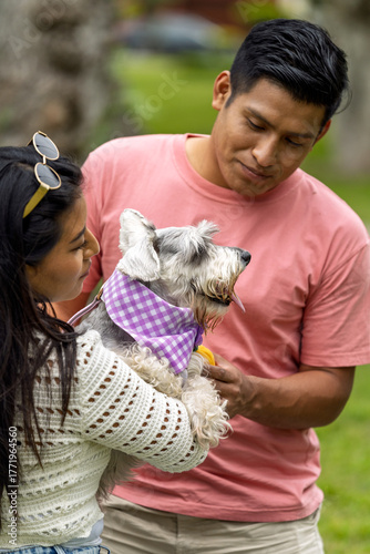 Young latino couple caring for pet dog in park