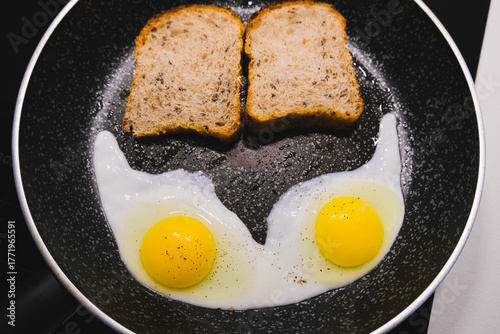 Two eggs and slices of toasted bread cooking in a pan — a cozy, simple breakfast captured from above.