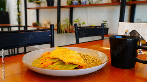 Platillo servido en plato artesanal con una omelette dorada acompañada de flor de calabaza y salsa verde.