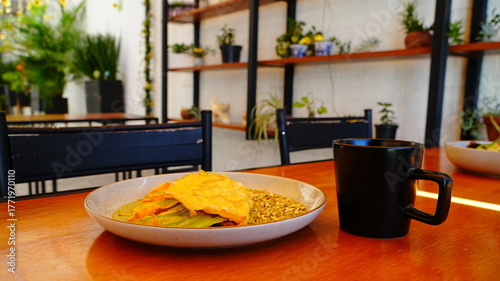 Platillo servido en plato artesanal con una omelette dorada acompañada de flor de calabaza y salsa verde.