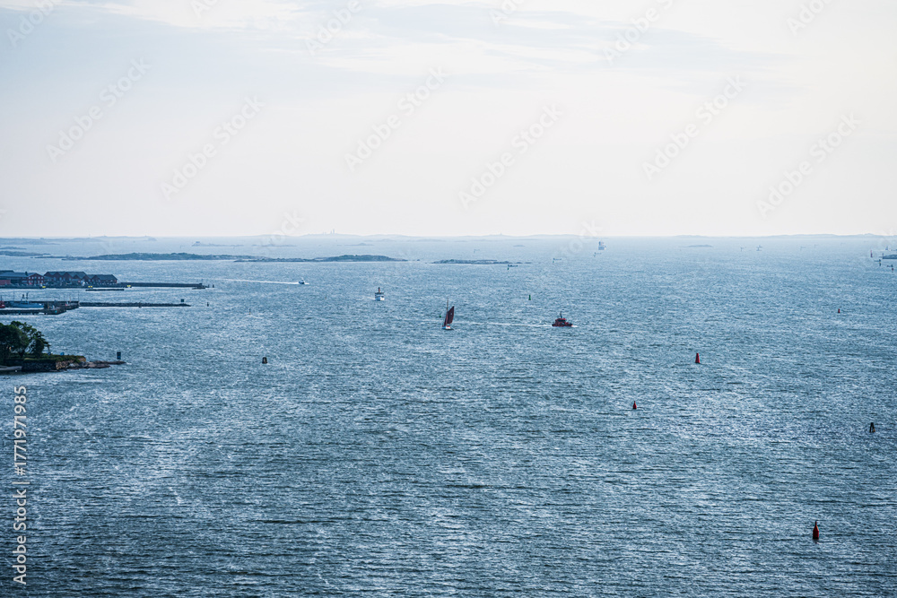 Obraz premium Overcast view of coastal inlet with scattered boats.