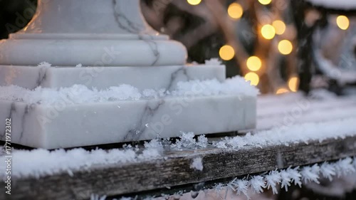 Elegant marble fountain base covered in delicate frost and snow with soft bokeh fairy lights in the background creating a magical winter atmosphere for holiday celebrations Podium