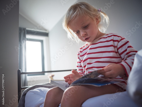 Little 4 year old girl sitting and reading a book