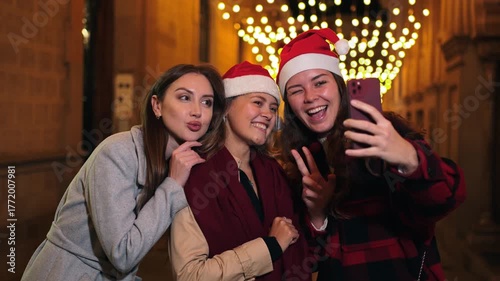 Three cheerful friends capturing a joyful selfie during the festive Christmas celebration, showcasing their happiness and friendship in a lively moment filled with laughter and excitement.