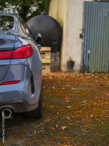 Light blue car parked in a country side home backyard with tall trees in the background. Living in peaceful rural side away from noisy town concept.