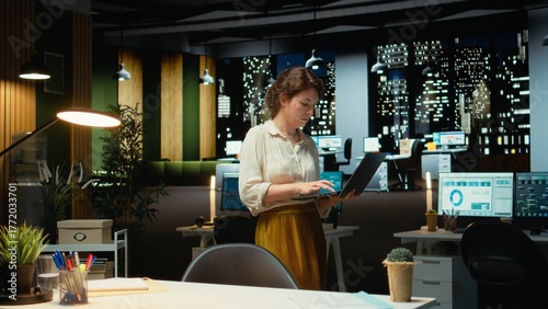 Foto Businesswoman at night reading finance data and proofreading reports, standing and making strategic decisions to help the multinational company achieve targets or strengthen objectives