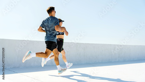 Couple jogging on a rooftop with clear blue sky in a city