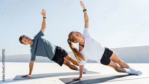 Photos Fitness enthusiasts performing side planks on mats in a bright outdoor setting a