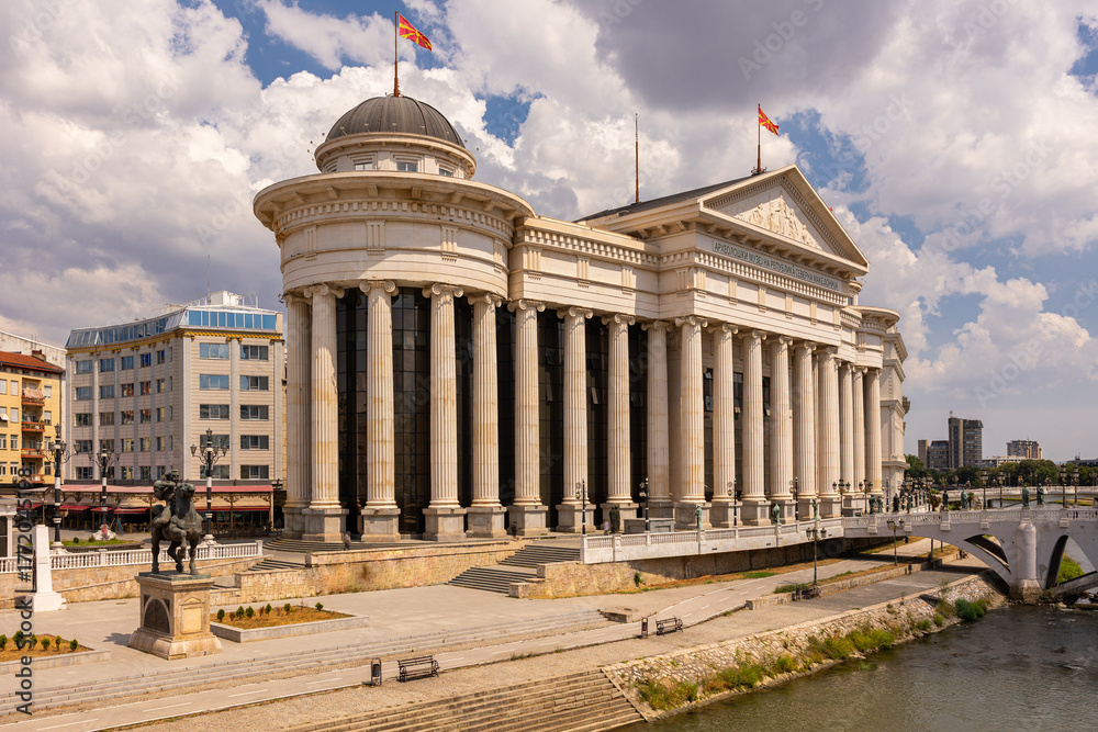 Naklejka premium Scenic view of Archaeological Museum of Macedonia with elegant neoclassical columns and dome standing in Skopje by Vardar River on bright summer day