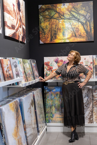 Woman admiring art in a gallery filled with vibrant paintings during an autumn-themed exhibition
