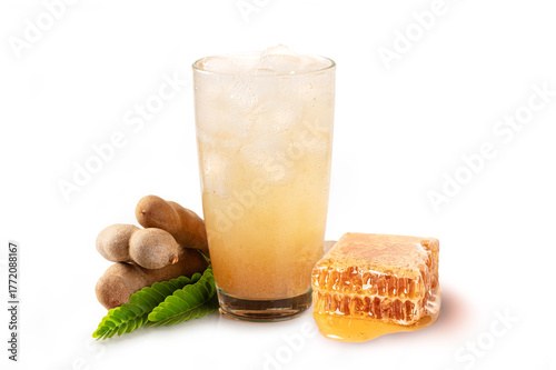 Glass of tamarind juice with tamarind pod and honey comb on white background.