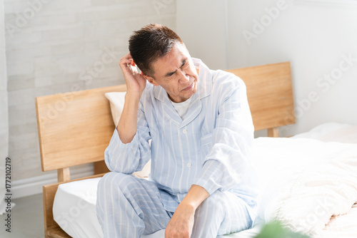 起きてベッドの上で悩んでいる男性