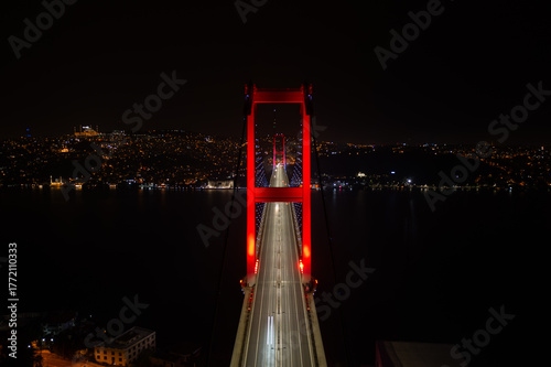 Aerial panoramic drone view of the 15 July Martyrs Bridge (Bosphorus Bridge) at night, connecting Europe and Asia in Istanbul, Turkey