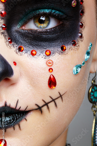Halloween beauty close-up photography of female face. Woman adorned with Santa Muerte makeup.