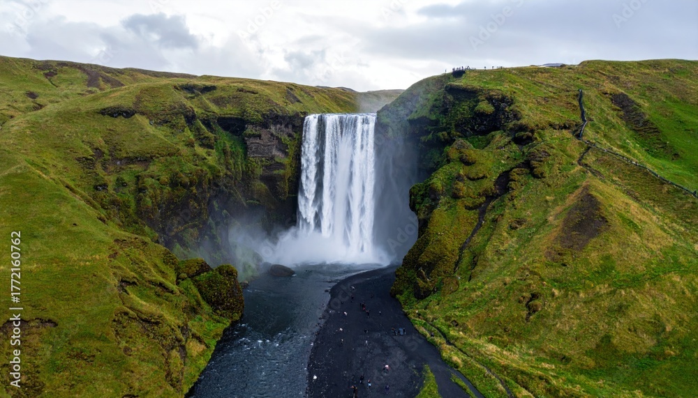 Obraz premium Aerial view of a majestic waterfall cascading down a lush green hillside