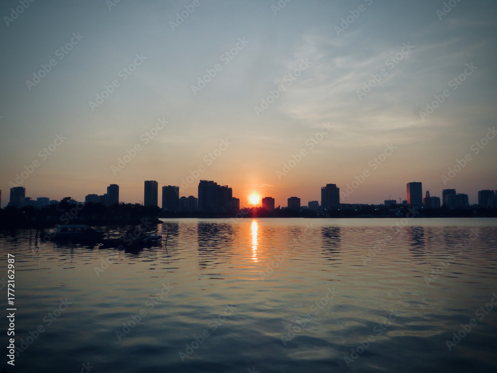 Naklejka premium Cool-Tone Sunset Over City Lake (Modern Cinematic Color Grade) on West Lake in Hanoi, Vietnam