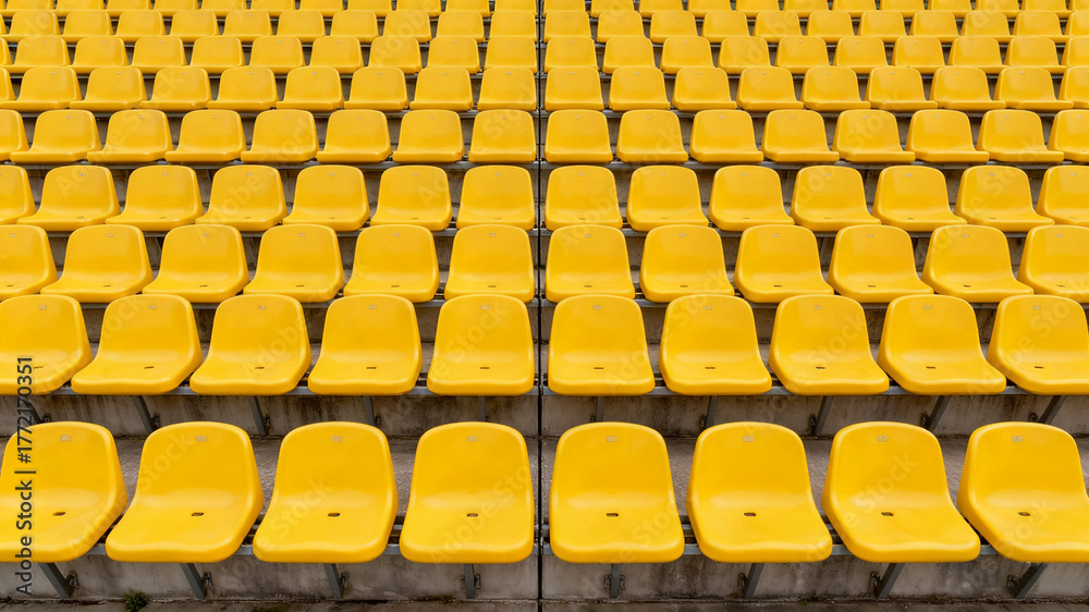 Naklejka premium Symmetrical yellow stadium seats from above, a serene geometric pattern of empty spaces 
