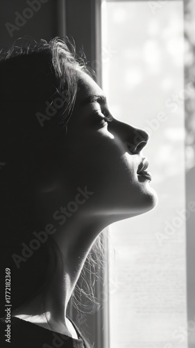 Monochromatic portrait captures woman in contemplative mood by window light