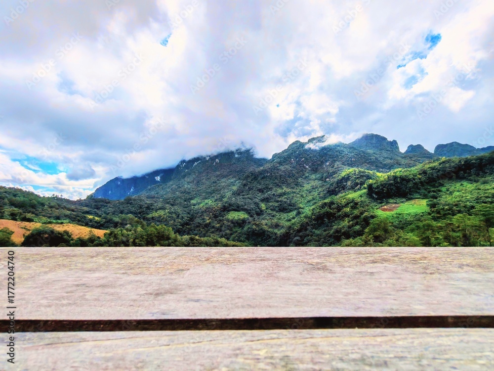 Fototapeta premium Empty Wooden Table or Countertop with Blurred Lush Green Tropical Mountain Landscape and Sky Background for Product Display at Chiang Dao, Thailand.