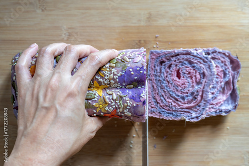 Top view of hands slicing homemade bread.
