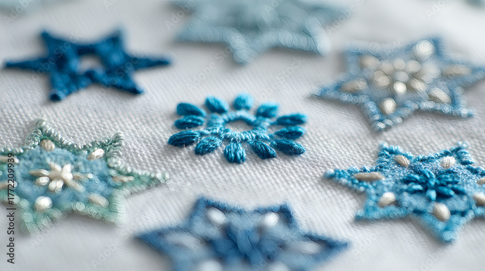 Fototapeta premium A close-up of delicate blue handmade embroidered stars and a snowflake motif on white fabric.
