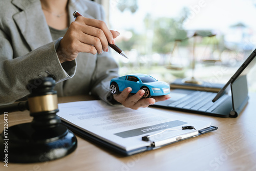 A lawyer signing a car contract with a gavel and a toy car on the desk, symbolizing car law, insurance, or legal agreement.