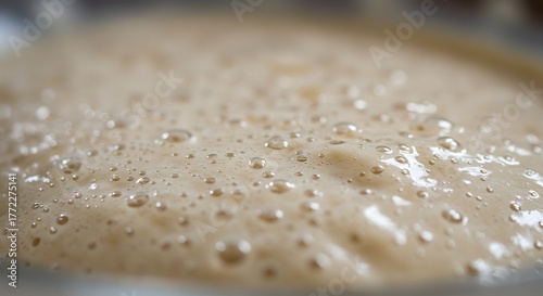 Close-up of a frothy, light-brown substance with bubbles, likely a fermented dough