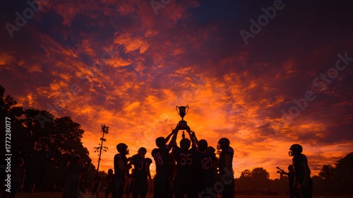 A victorious team lifts a gleaming trophy against a stunning sunset, their arms raised in celebration. The vibrant sky and silhouettes convey joy, achievement, and the thrill of sports triumph.