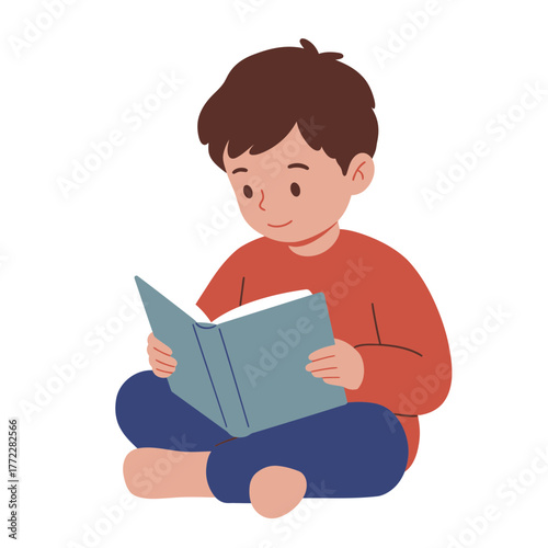 A young boy with brown hair sits cross-legged and engrossed in reading a book.