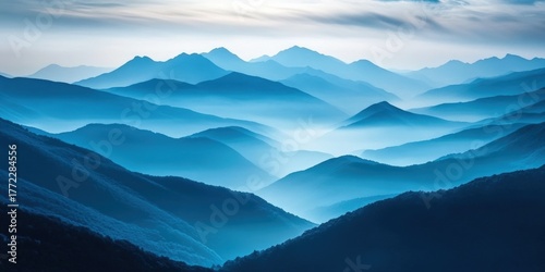 Serene blue mountains create a tranquil landscape, shrouded in mist and layered in shades of blue, evoking a sense of calm and connection to nature.